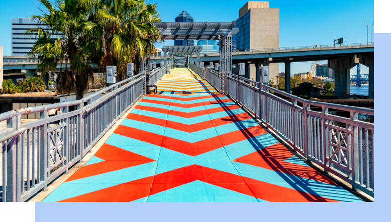 The colorful painted sidewalk of The Riverwalk with the skyline of Jacksonville, Florida.