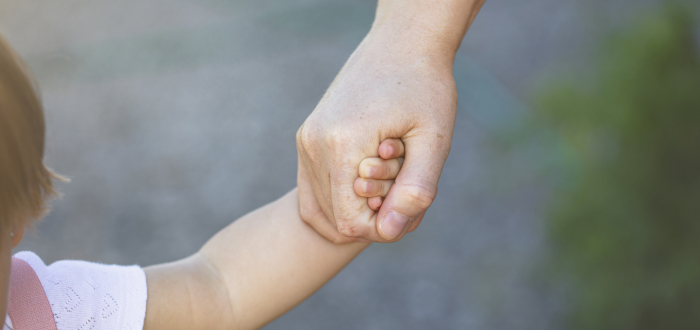 Parent holds hands with child