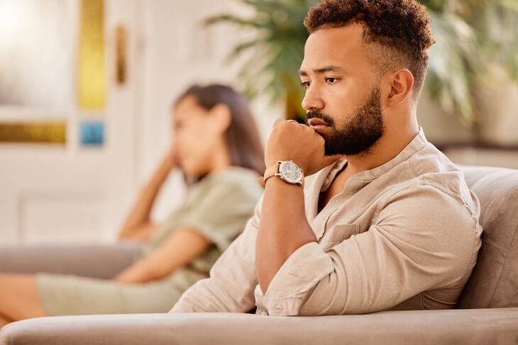 couple looking upset and sitting far apart on couch