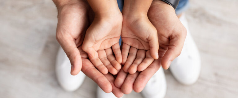 Care, Support And Growth. Cropped close up above top view of caring man holding girl's palms in hands, spending free time with daughter together at home. Children Custody Concept