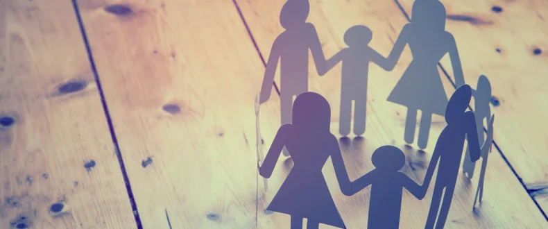 paper people all connected in a circle on a wood floor child sharing