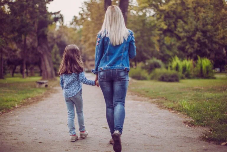 Mother and daughter walking together through a park